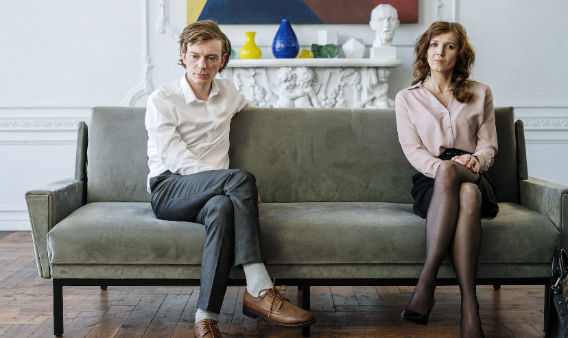 couple sitting on therapy couch with a big gap between them